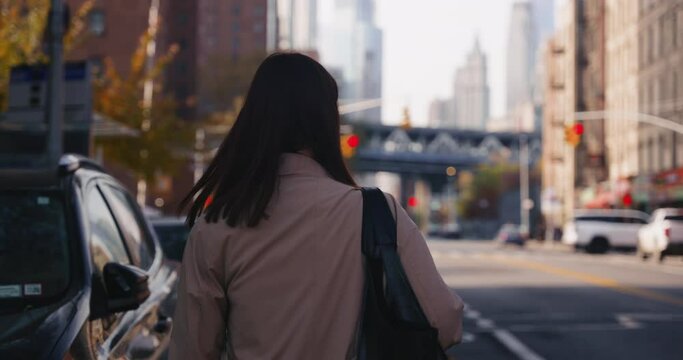 Beautiful Caucasian brunette female walks in busy street of New York and turns back to camera smiling