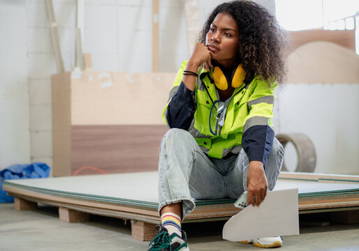 Break time. Multiethnic engineer woman sitting relax at factory floor take a break. Tired female multiracial technician foreman in uniform take rest after job done in manufacturing. Employee take rest
