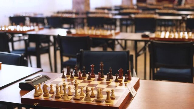 Chess tournament, kids and adults participate in chess match game outdoors in indoor hall, players of all ages play, competition in chess school club with chessboards on a table