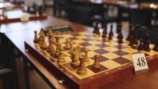 Chess tournament, kids and adults participate in chess match game outdoors in indoor hall, players of all ages play, competition in chess school club with chessboards on a table