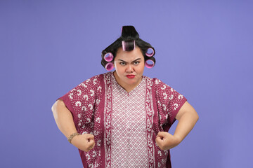 An Asian woman poses defiantly. Asian woman strong pose in front of the camera isolated in a purple background