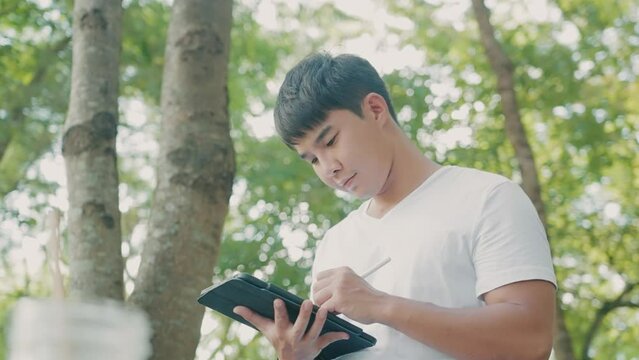 Asian man using wireless pen writing on digital tablet, online assignments, paperless education, soft files application for users, online sketch drawing, work smart with modern technology gadgets.