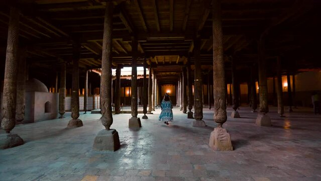 Woman in the Hall of wooden columns in Juma Mosque in Khiva