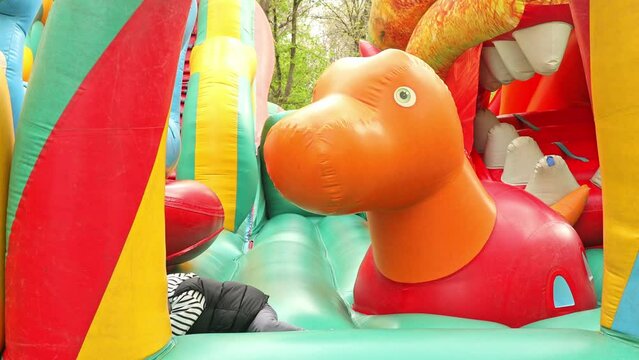 Child jumping on colorful playground trampoline. Kids jump in inflatable bounce castle on kindergarten birthday party Activity and play center for young child. Little boy playing outdoors in summer.
