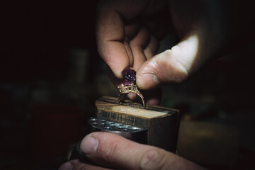 master of jewelry manually inserts gems into the frame of future jewelry. Working desk for craft...