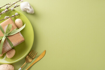 Simple Easter display concept. Top view of minimalist wrapped gift in plate, cutlery, rabbit miniature, quail eggs, pussy willow stems, on pistachio background with vacant space for text or marketing