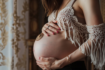 mother holding her pregnant belly, touching maternity image of motherhood with a bohemian style touch.