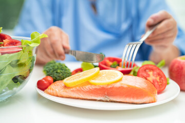 Asian elderly woman patient eating salmon steak breakfast with vegetable healthy food in hospital.