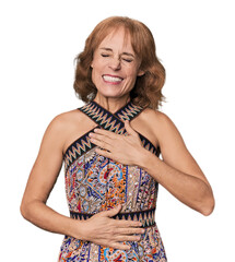 Redhead mid-aged Caucasian woman in studio laughs happily and has fun keeping hands on stomach.