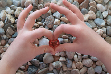 Red glass heart on the stone nature background.