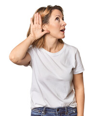 Blonde middle-aged Caucasian woman in studio trying to listening a gossip.