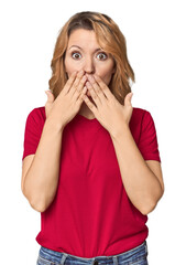 Blonde middle-aged Caucasian woman in studio shocked, covering mouth with hands, anxious to discover something new.