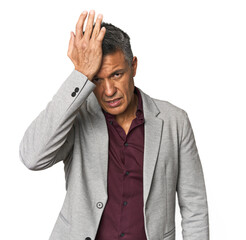 Middle-aged Latino man forgetting something, slapping forehead with palm and closing eyes.