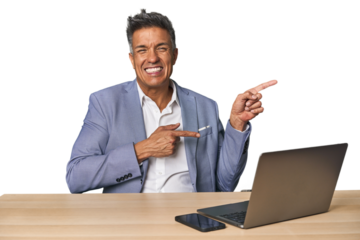 Elegant businessman at desk with laptop pointing with forefingers to a copy space, expressing excitement and desire.