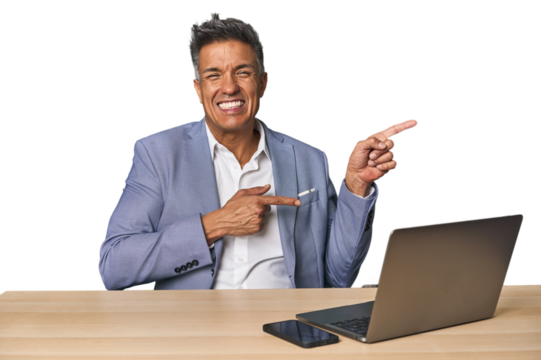 Elegant businessman at desk with laptop pointing with forefingers to a copy space, expressing excitement and desire.
