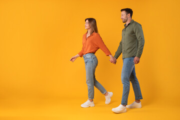 Excited european spouses stroll hand in hand, walking and gazing at free space, against vibrant...