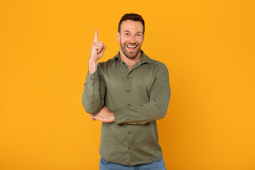 Excited European man enthusiastically points upward, brimming with inspiration and looking at...