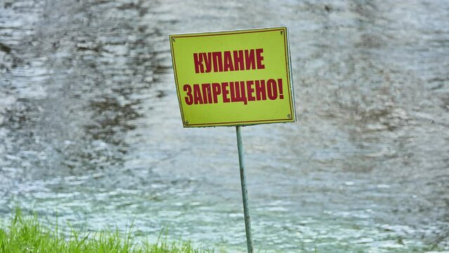 Signs warning about ban on bathing in Russian. Coast of fast river. Red letters on yellow background: Bathing is prohibited.