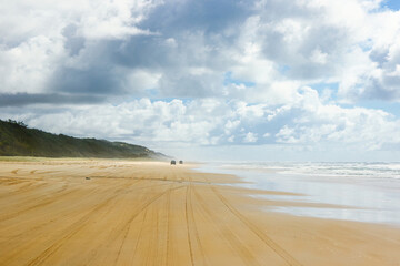 4-wheel drive pickups travelling on the sandy highway of the 75-mile beach on the east coast of Fraser Island, Queensland, Australia - obrazy, fototapety, plakaty
