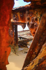 Rusty crumbling piece of the SS Maheno shipwreck half buried in the sand of the 75 mile beach on...