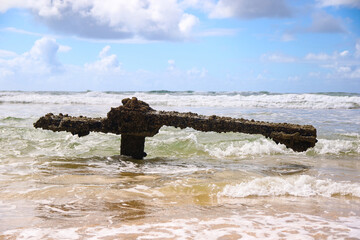 Rusty crumbling piece of the SS Maheno shipwreck half buried in the sand of the 75 mile beach on...