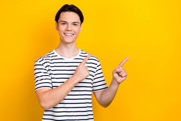 Portrait of toothy beaming student wear stylish t-shirt indicating at discount empty space isolated on bright yellow color background