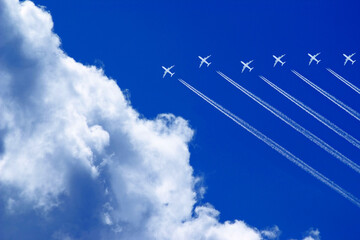 seven aeroplanes with contrails flying high in the blue sky in formation