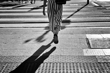 Woman legs walking downtown on the crosswalk in a European city
