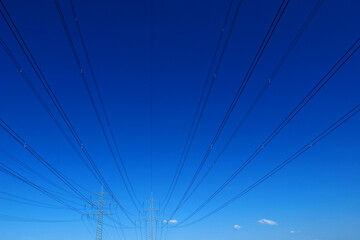 High-voltage lines with pylons against a blue sky