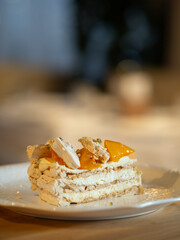Puff layered cake with cream of cream-cheese, decorated fresh persimmons. Delicious and eye-catching piece of layered cake decorated orange persimmons
