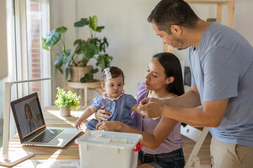 Latin family giving treatment to their baby in online consultation with doctor through laptop