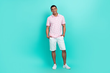 Fototapeta na wymiar Full length photo of positive man wear flamingo print t-shirt white shorts hold arms in pockets isolated on turquoise color background