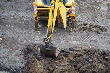 Fototapeta premium Yellow excavator doing earthworks, excavator bucket digging soil, excavator on a construction site