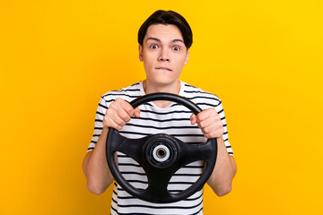 Portrait of stunned guy with brunet hair wear stylish t-shirt hold steering wheel look at crash isolated on yellow color background