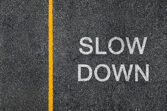 Slow Down written on the asphalt street. Traffic lane with yellow separation line. Road safety graphic texture concept	