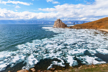 Baikal Lake in spring. Beautiful landscape of the famous Shamanka Rock - a natural landmark of Olkhon Island during the May ice drift. Spring travel and recreation. Natural seasonal background