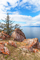 Beautiful spring landscape of Baikal Lake in May. Typical view of Olkhon Island with round red stones and larch trees on rocky shore of Small Sea. Natural background. Spring travel, hiking, outdoors