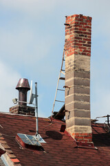 Old brick smokestack on a rooftop with a metal ladder for servicing