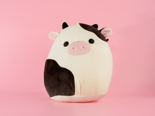kids Black and white cuddly funny soft toy cow bull isolated on a pink background