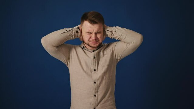 Man in His 30s Blocking Out Sound Against Blue Background