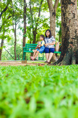 Adorable little asian daughter relax in city publice green park with mom - 742699111