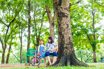 Adorable little asian daughter relax in city publice green park with mom - 742701562