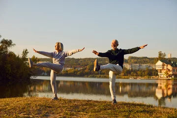 Fotobehang Active sporty senior couple doing stretching exercising in nature. Happy smiling elderly man and woman in sportswear having sport workout in park. Outdoors training and fitness in retirement concept. © Studio Romantic