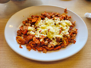 Plate of Spicy Al Pastor topped with cheese, served with fresh salsa and onions
