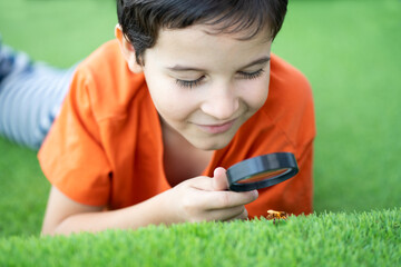 Shot of an inquisitive little boy exploring the woods with a magnifying glass