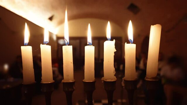Menorah candlestick in mystic freemasonry lodge, religious ritual in freemason temple, dark illuminated lodge with blurred people sitting around and burning candles, religious brotherhood concept