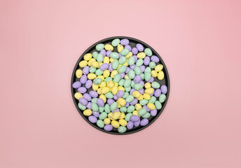 Top view of colourful easter eggs in black plate on pink background. Creative easter composition, spring, copy space, flat lay.