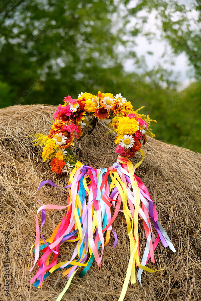 Wall mural flowers wreath with colorful ribbons on haystack. summer background. floral crown, symbol of summer 