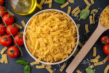 Raw uncooked Mafaldine pasta with ingredients for cooking. Short italian Mafaldine pasta with olive...