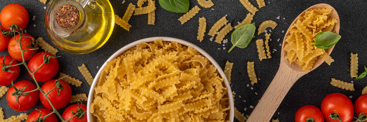 Raw uncooked Mafaldine pasta with ingredients for cooking. Short italian Mafaldine pasta with olive...